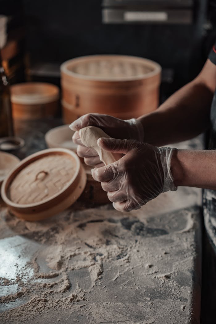 Chef skillfully shaping dumplings on a floured table in a kitchen scene.