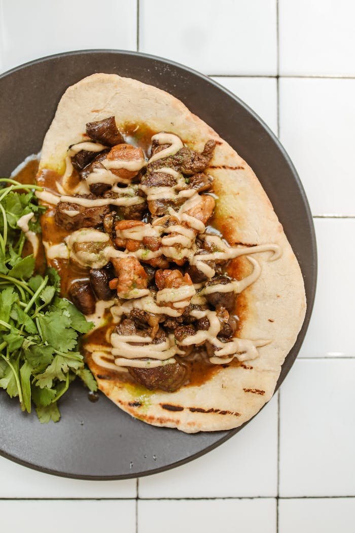 Savory Jerusalem mixed grill served on pita with fresh herbs for garnish.